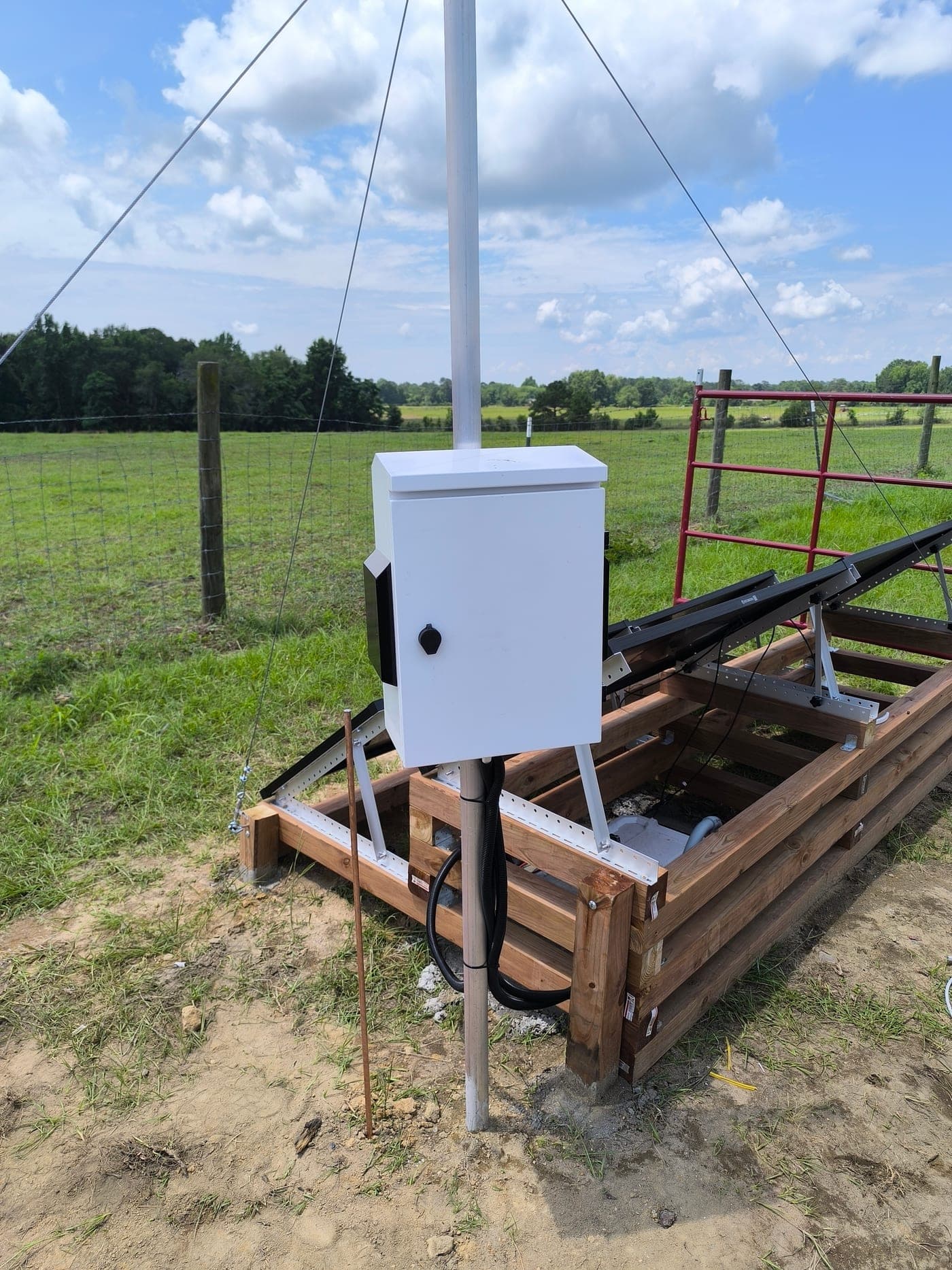 Weatherproof field enclosure housing wireless-link electronics and power on a guy-wired mast in the pasture